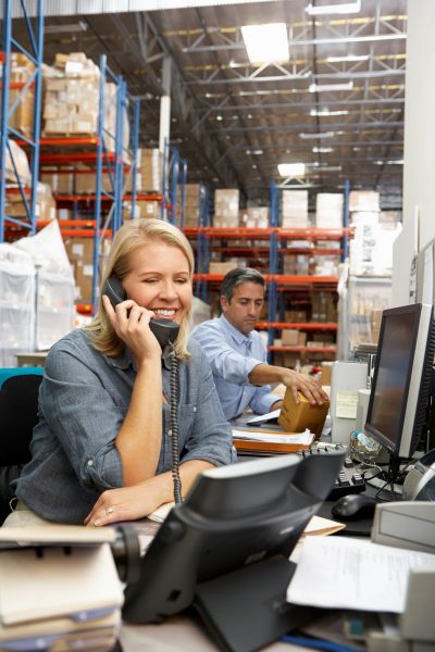 businesswoman-working-at-desk-in-warehouse-PK3QYHP